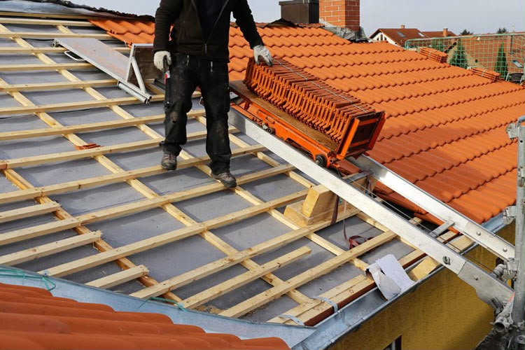 Pose de tuiles à l'aide d'un monte-matériaux sur un chantier à Massy
